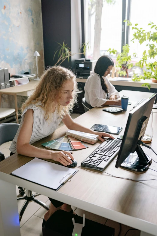 three women sitting at a desk working on some things