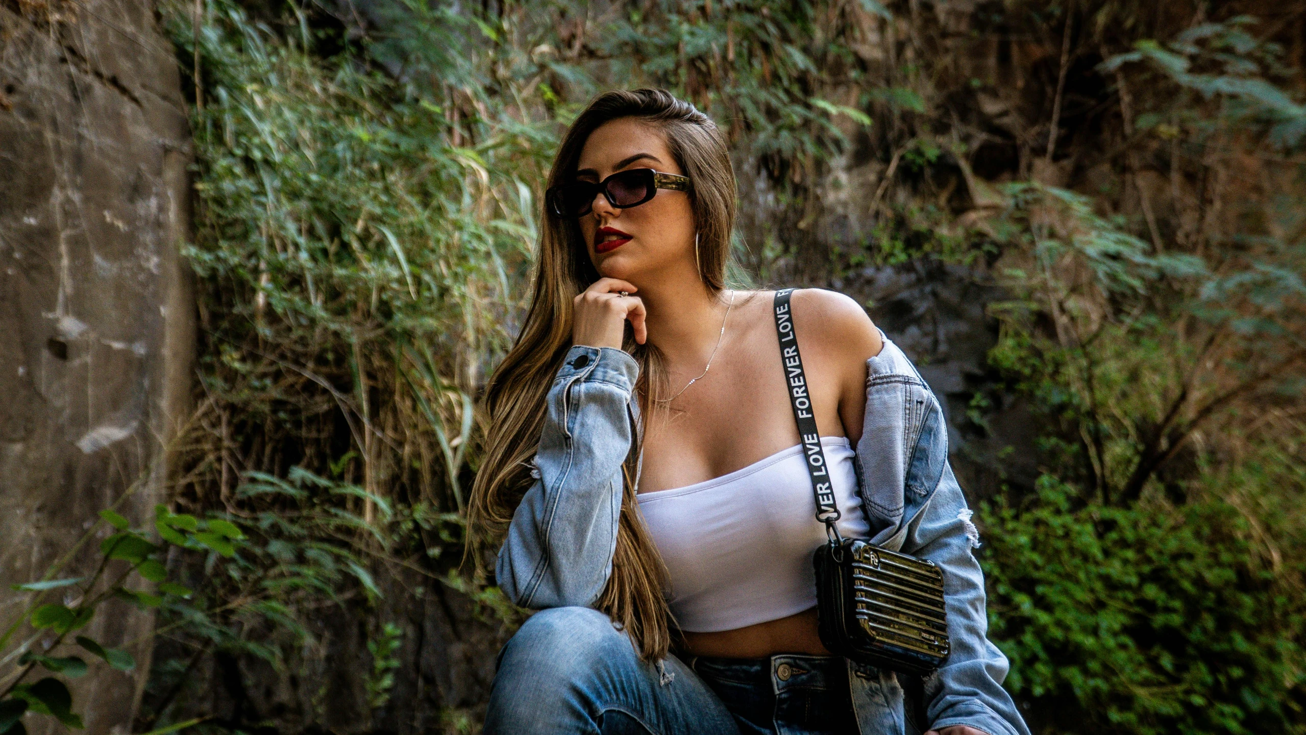 a woman sits on a curb in a forest