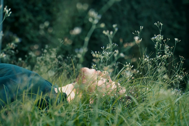 a person laying in the grass with their eyes closed