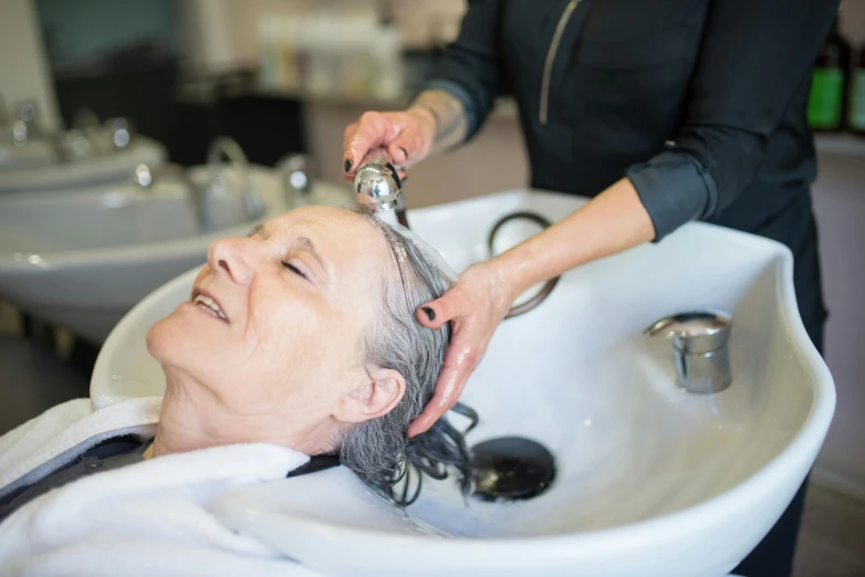 a woman is getting her hair brushed by a hairdresser