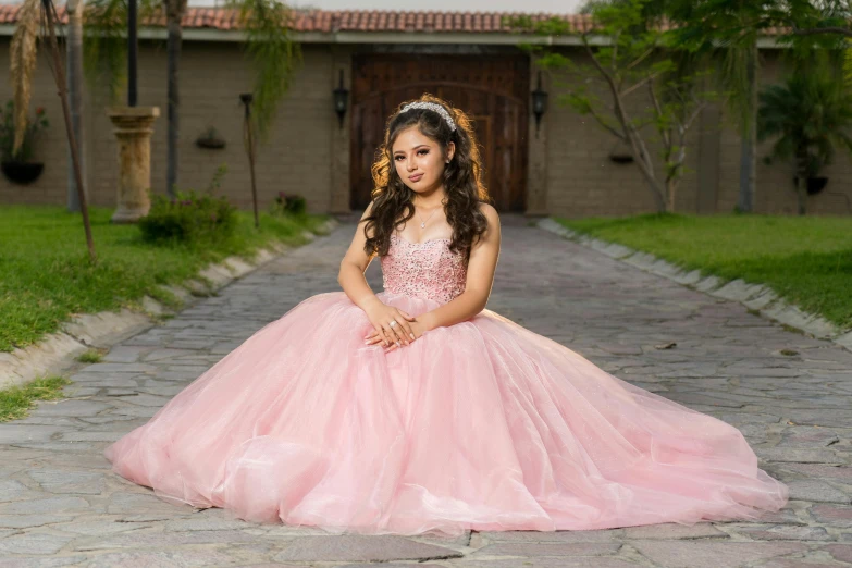 girl in pink gown poses at the entrance of her home