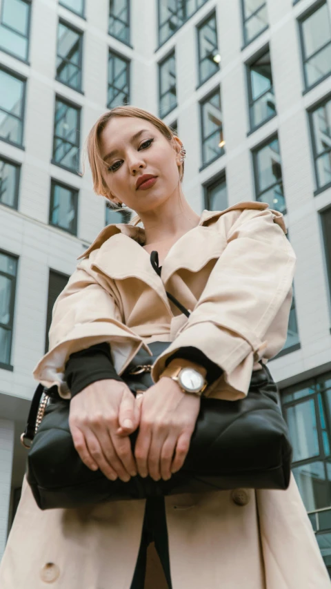 a young woman dressed in beige with large black purse posing for a po