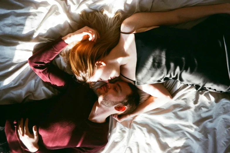 a man and woman lying on bed with sheets over head