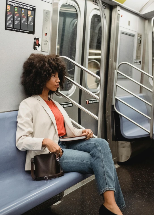 the woman sits on a subway train reading her electronic device