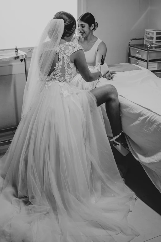 a bride sitting next to her maid in the hospital