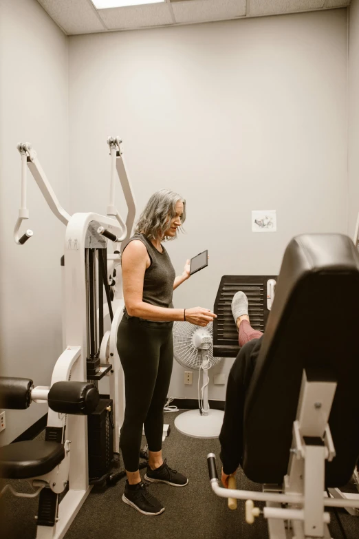 an older woman stands next to exercise equipment