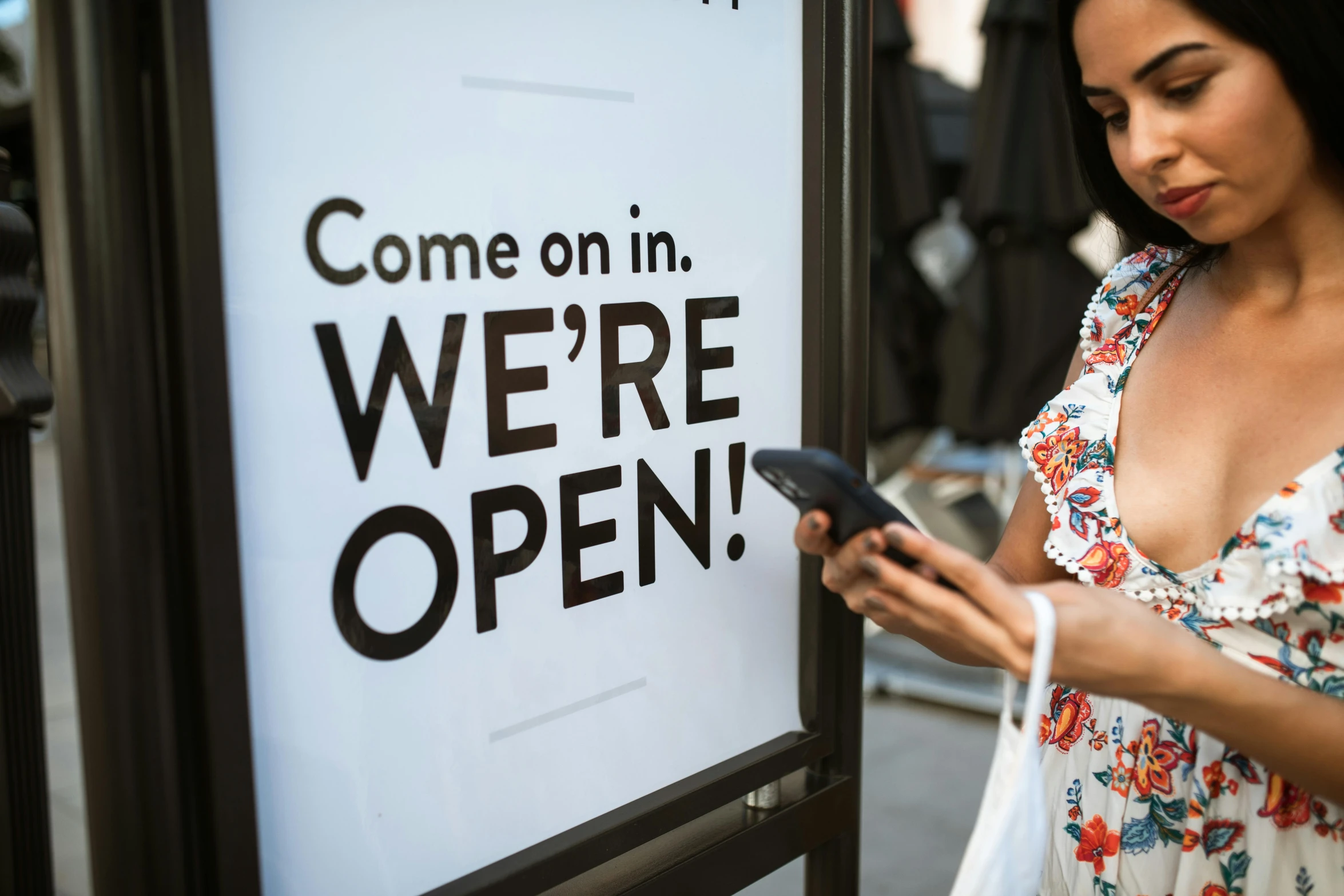 the woman is checking her phone near a sign