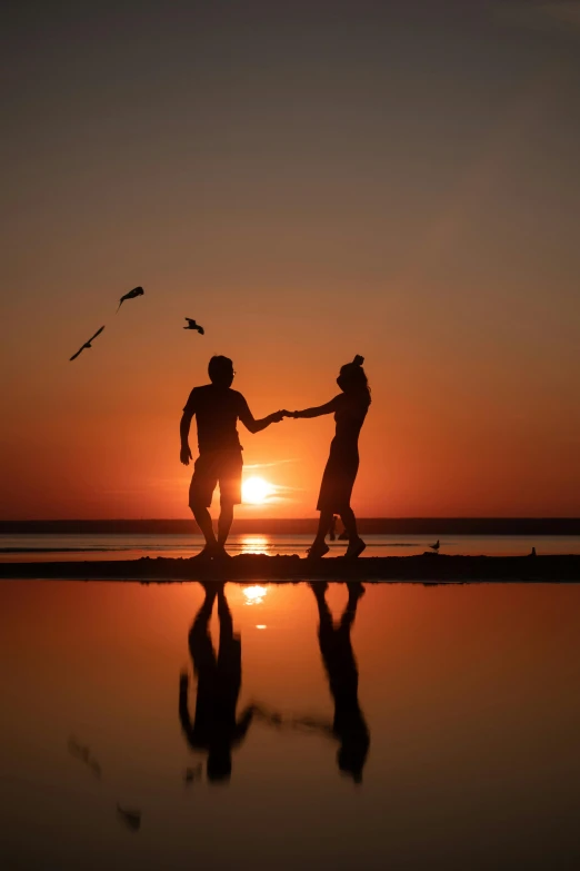 two people with arms around each other standing near a body of water