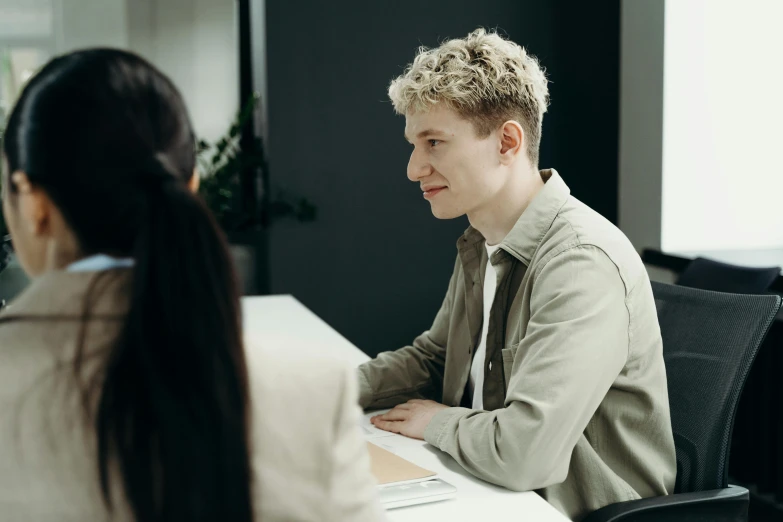 two people sitting at desk facing each other