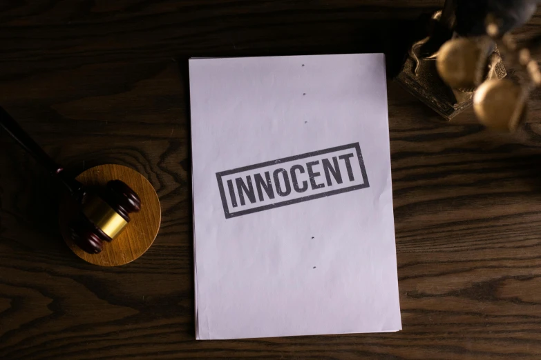 a piece of paper with the word innocent on it and a judges hammer next to it