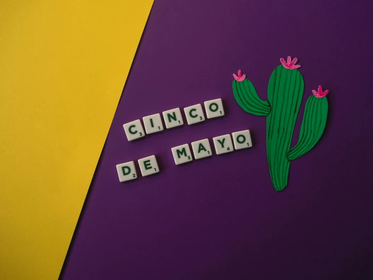 a set of letter tiles sitting next to a small cacti