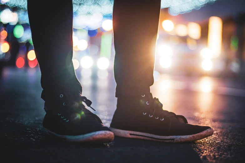 pair of feet in boots standing on street at night