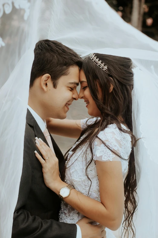 a couple is emcing under a veil in a po