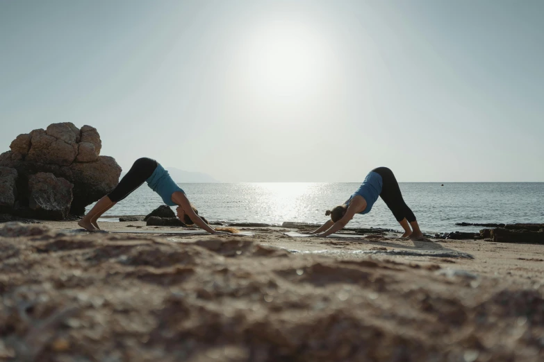 two people stretching their muscles in front of the ocean