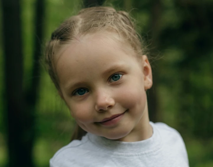 a small smiling child with blond hair standing