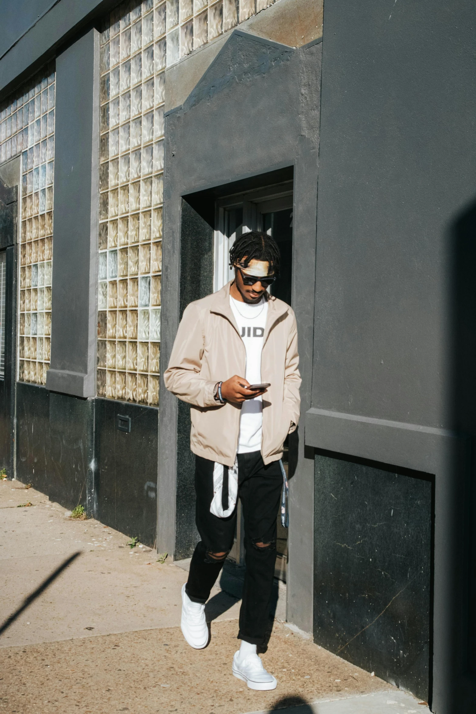 man standing in doorway with sunglasses on his head and using a cell phone