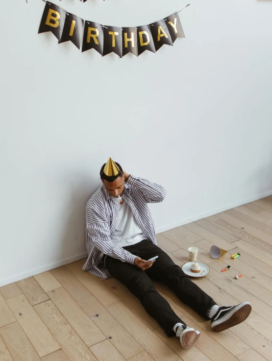 man in party hat sits down looking at a book