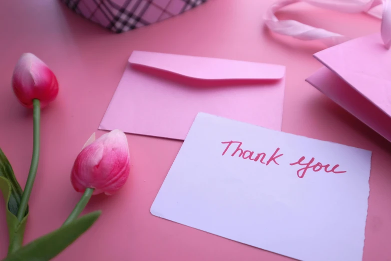 a table holding pink paper and pink flowers