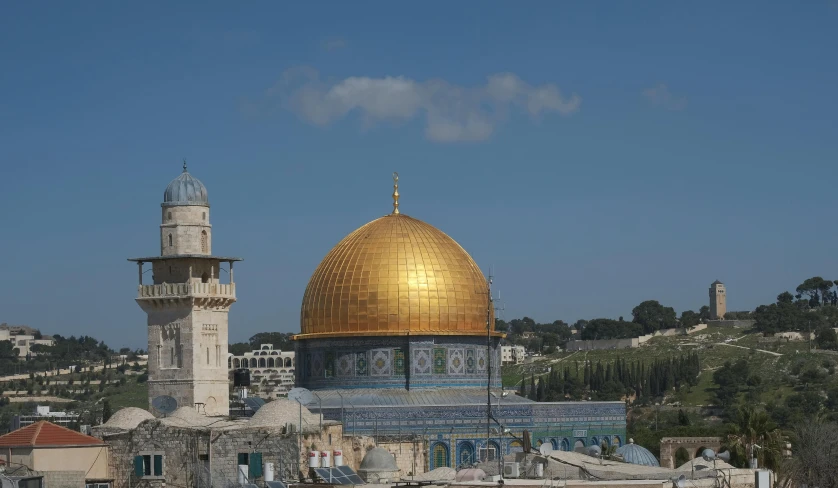 a gold dome above several small buildings on the hillside