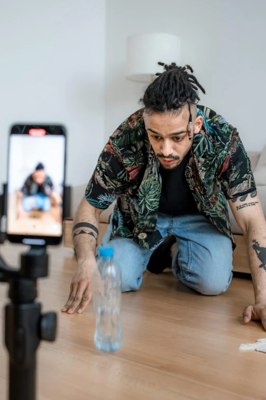 a man with dreadlocks crouched down and looking at soing on the table