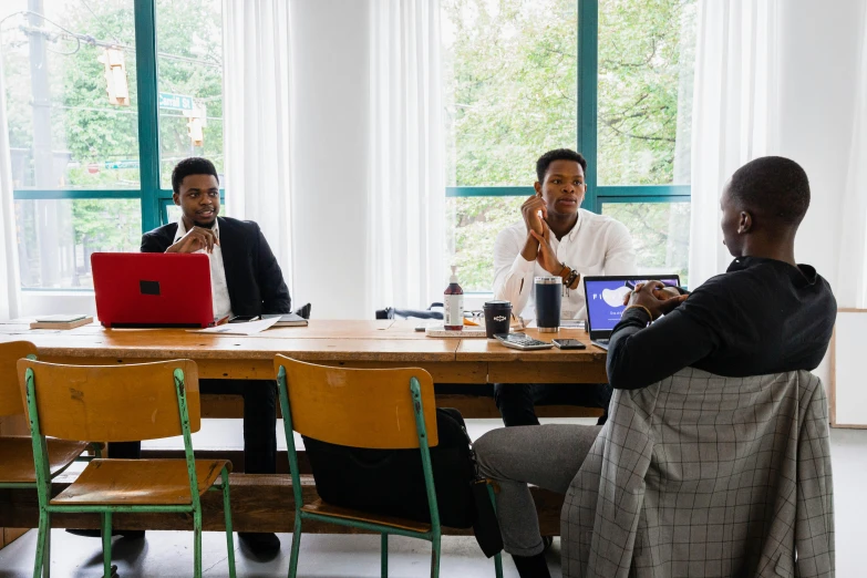 people are sitting at a table working on their computers