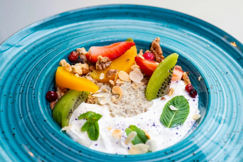 a blue plate topped with fresh fruit, nuts and yogurt