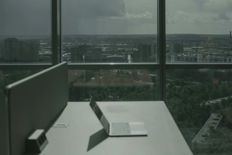 a laptop sitting on top of a desk near a window