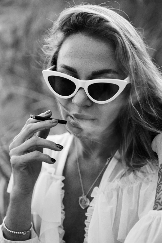 woman wearing white and smoking a cigarette in her hands
