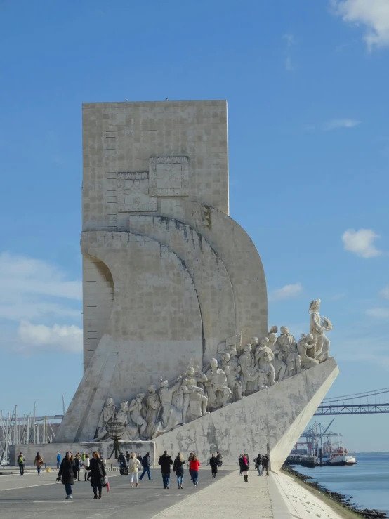 many people walk up and down a sidewalk near a monument