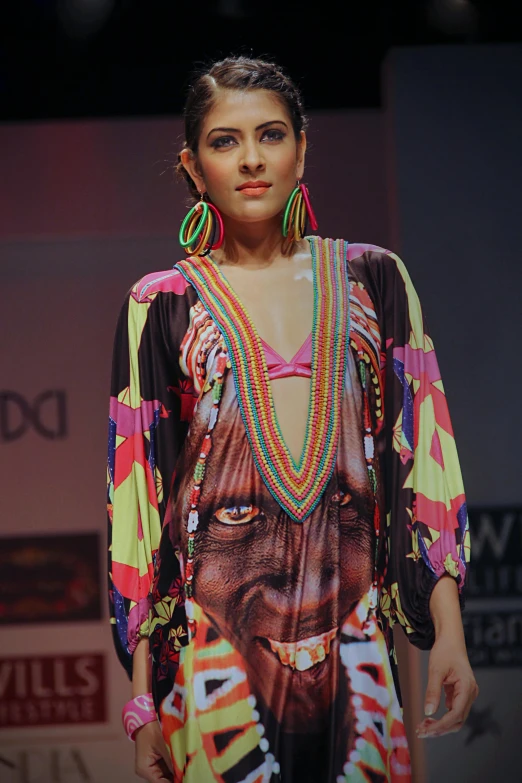 a woman with necklaces on walking down a runway