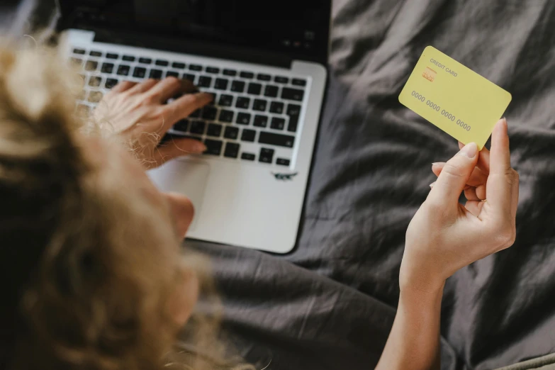 person using a computer holding a yellow card