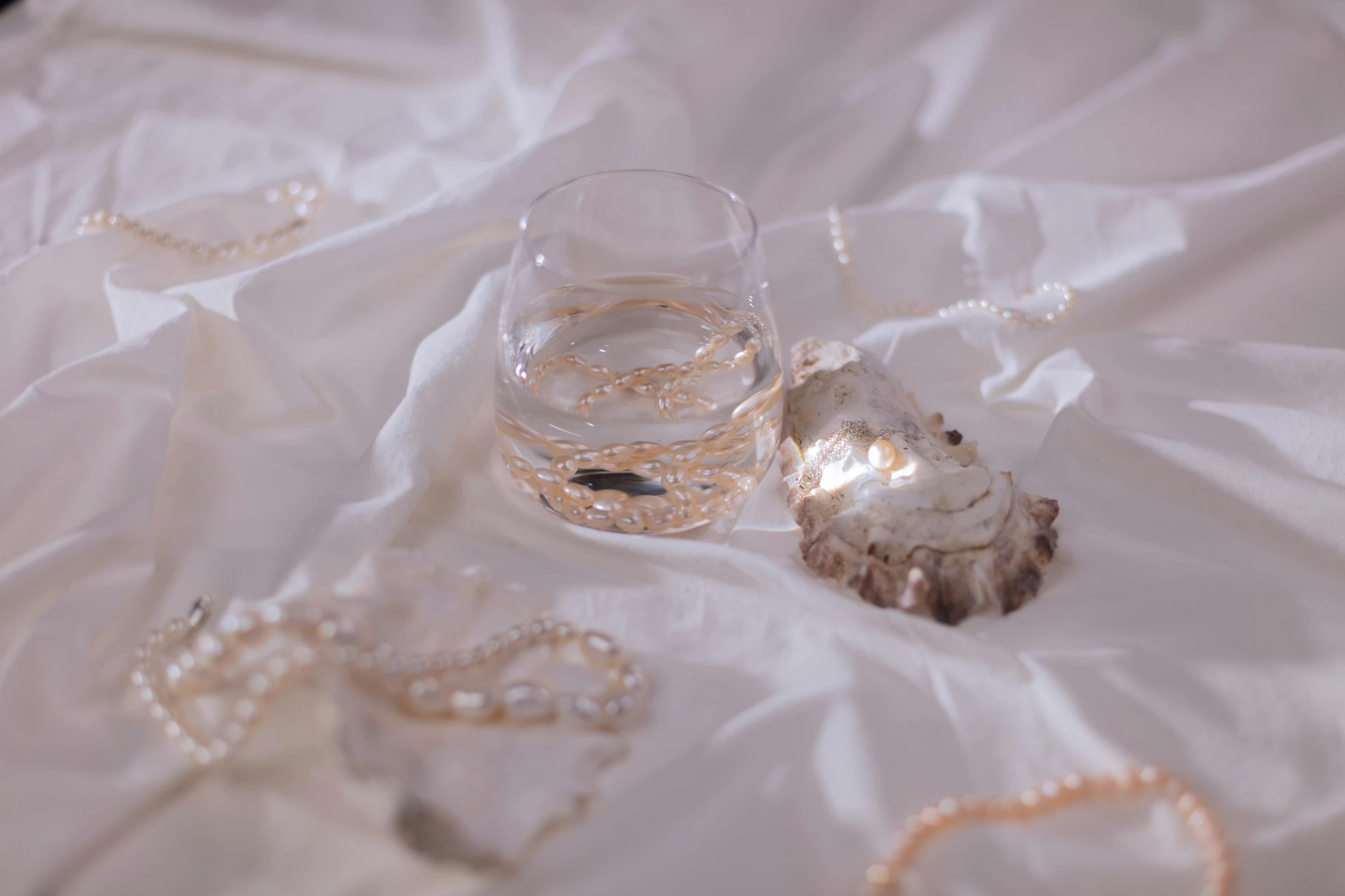 two seashells and some pearls on a white cloth