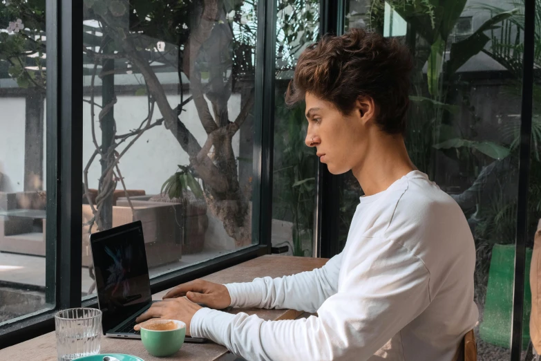 the woman sits at a table in front of her laptop computer