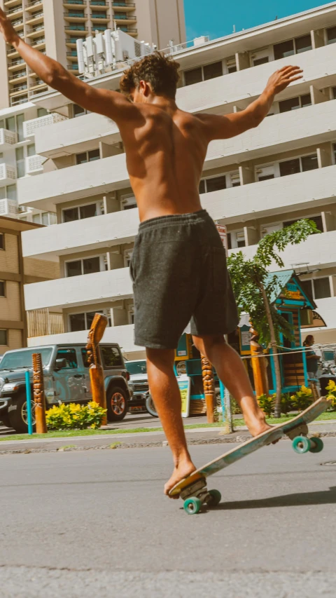 a man in shorts riding on a skateboard down the street