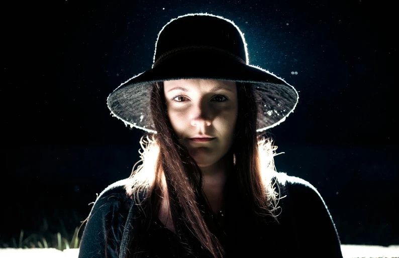 a person wearing a hat and standing in a dark area