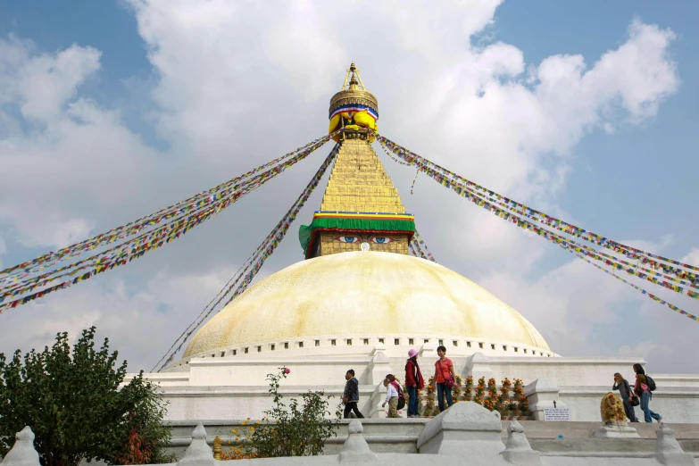 several people walk down a steeple next to buddhist flags