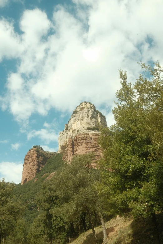 a large rock with trees in the foreground