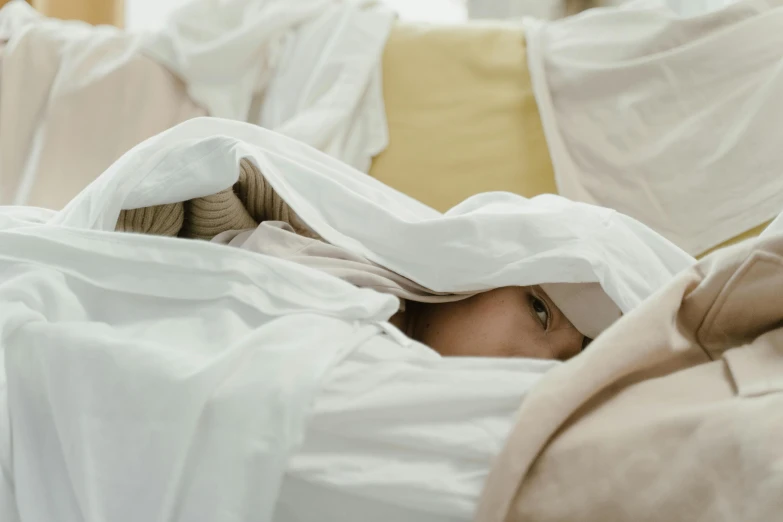 a woman is under the covers in a bed