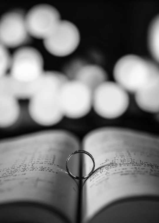 a ring sitting on top of a book with many lights in the background