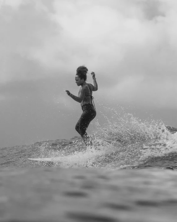 a woman is surfing in the ocean on a very cloudy day