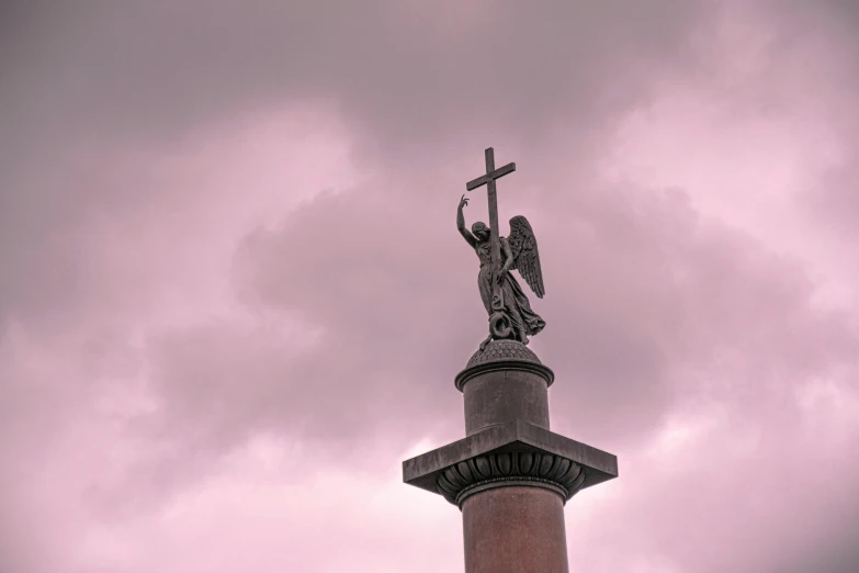 a statue on top of a stone pillar under a cloudy sky