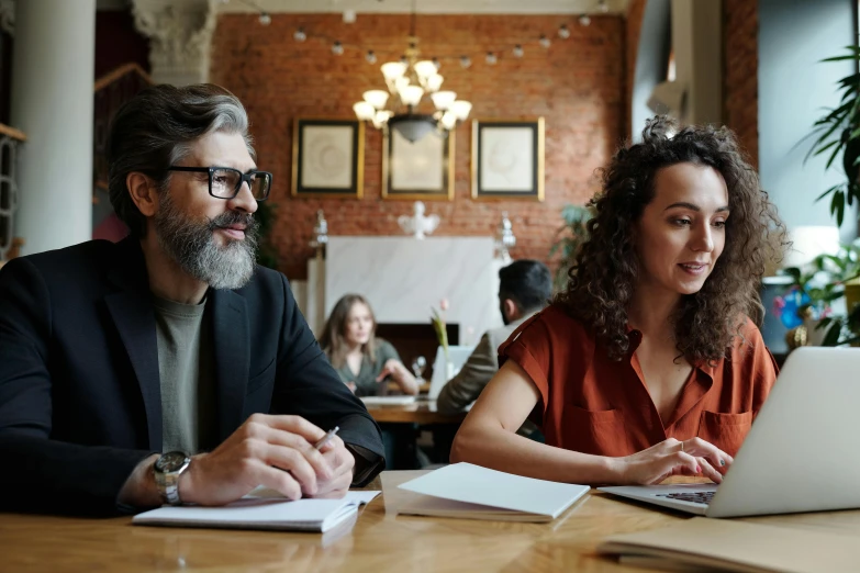 a man and woman sitting together in front of a laptop computer