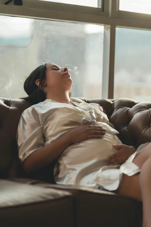 the pregnant woman is resting on the sofa