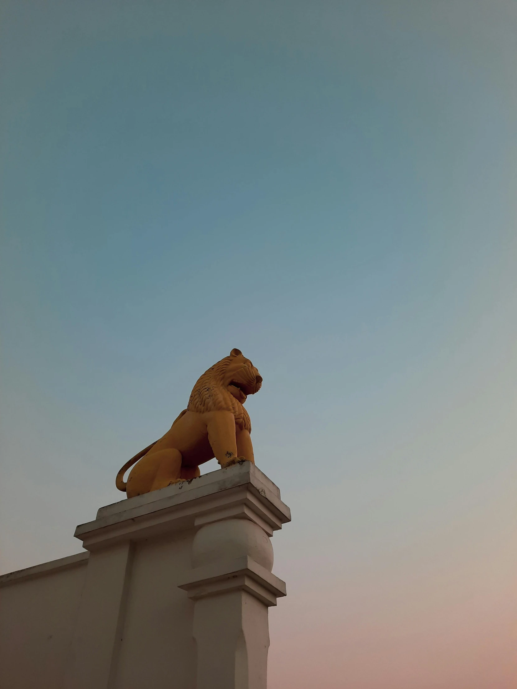 a yellow lion statue sits atop a building