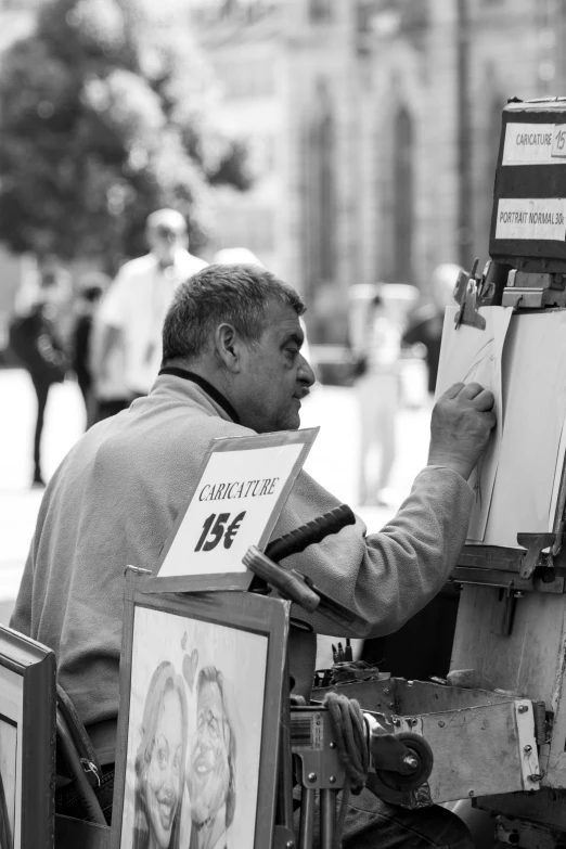 man painting pictures on easels with a crowd in the background