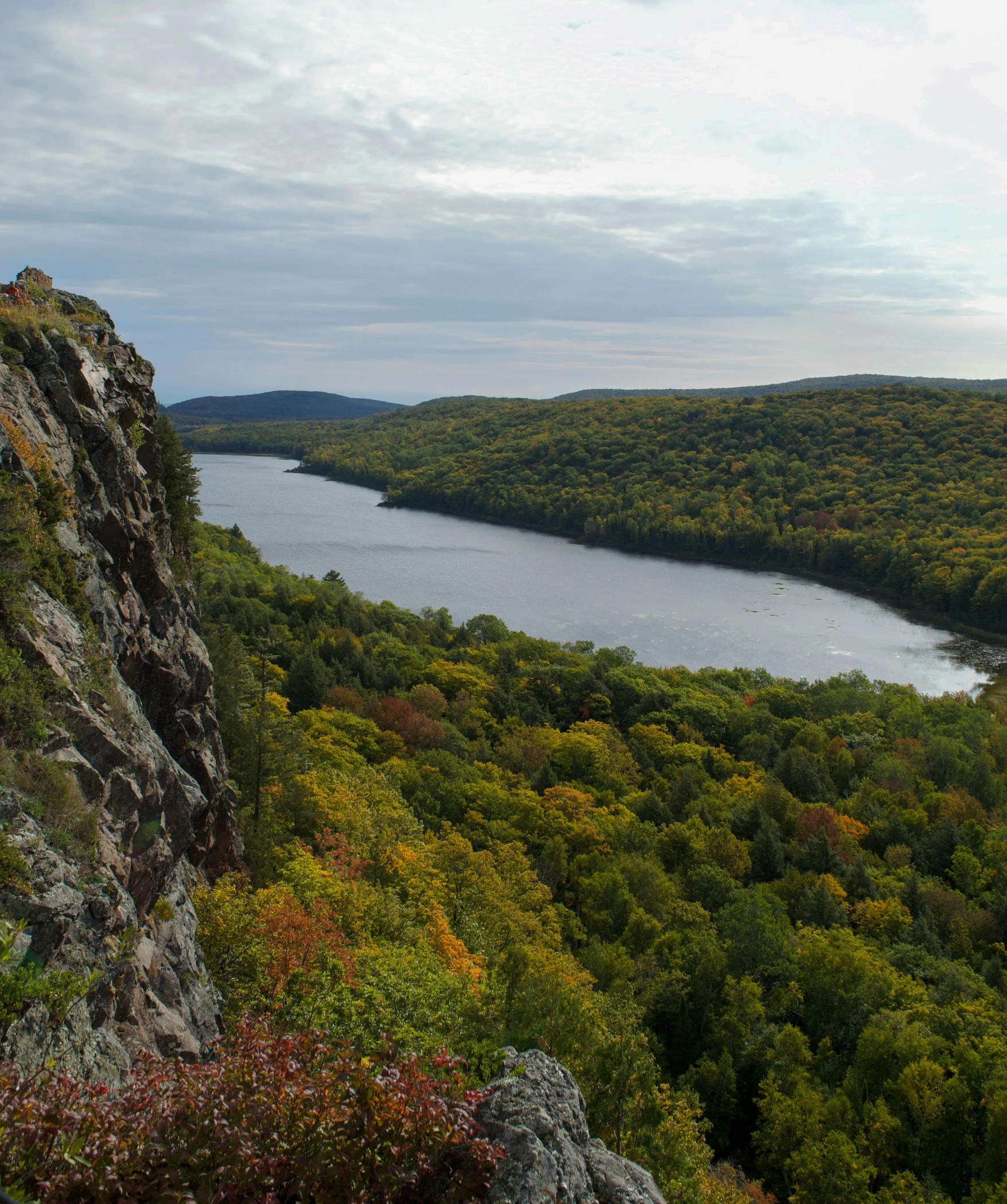 a mountain side overlooking a body of water in the middle of trees