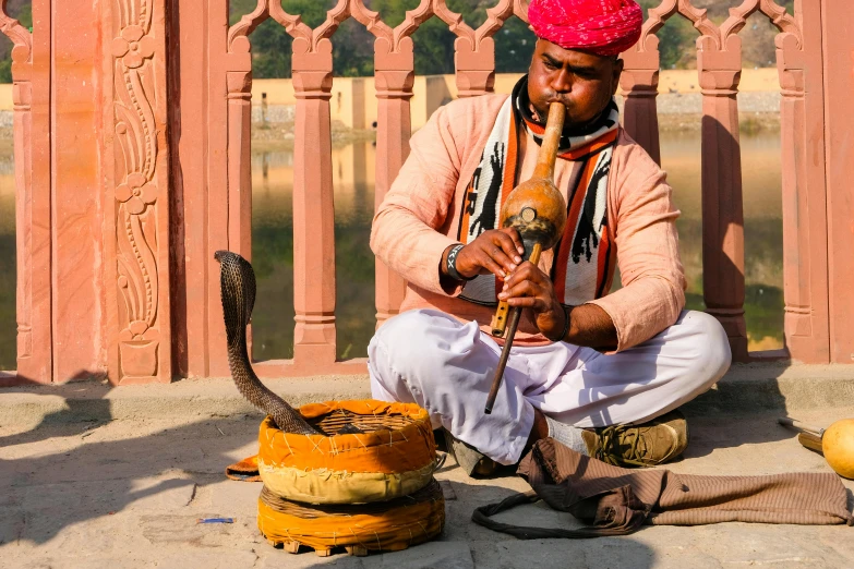 the man sits on the ground next to a small fire hydrant