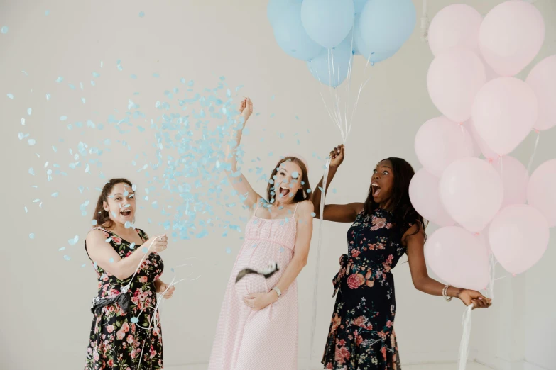 three women smile and fly a couple of balloons while laughing