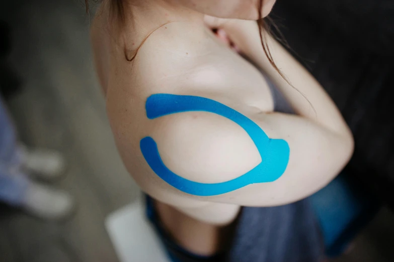 a woman is holding onto a blue arm with the letter c painted on her chest