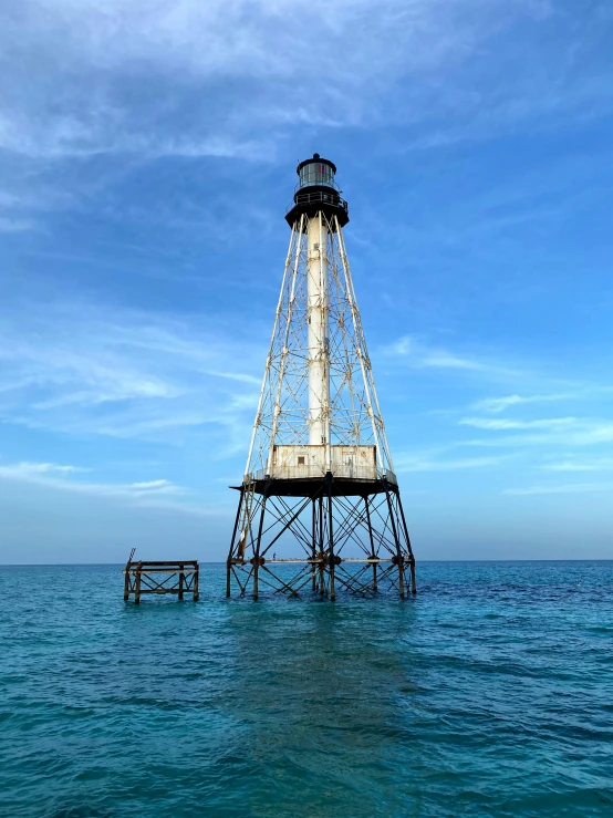 a white light house sitting on the side of a pier